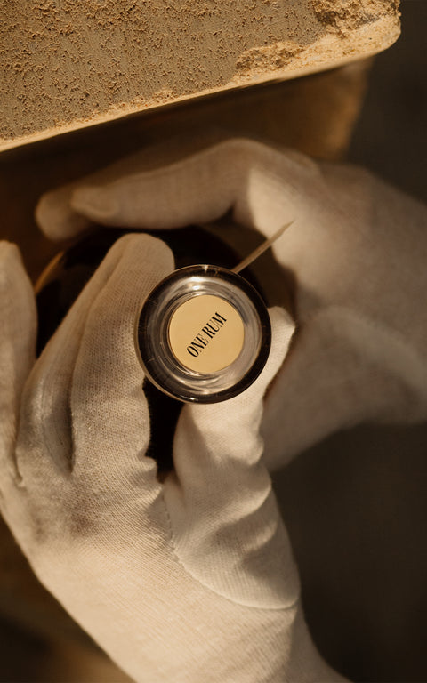 Nahaufnahme des eleganten Glasverschlusses einer ONE RUM Flasche, mit feinem „ONE RUM“ Schriftzug. Der Verschluss betont die Exklusivität und Detailgenauigkeit der Marke.