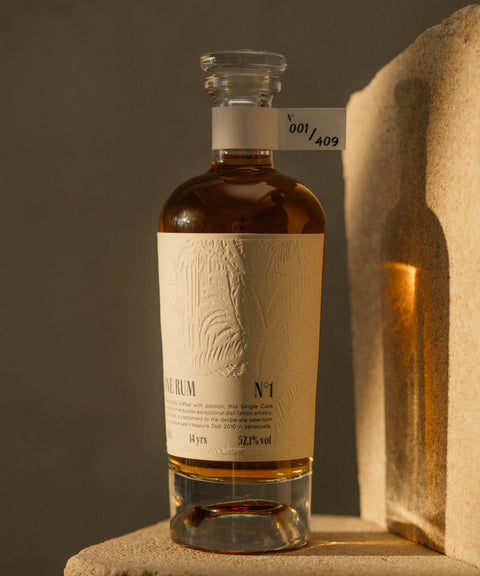 ONE RUM No. 1 Flasche mit elfenbeinfarbenem Etikett und Seriennummer 001/409, auf einem Sandsteinblock arrangiert. Diese 14-jährige, limitierte Abfüllung betont die Qualität und Rarität des Rums.
