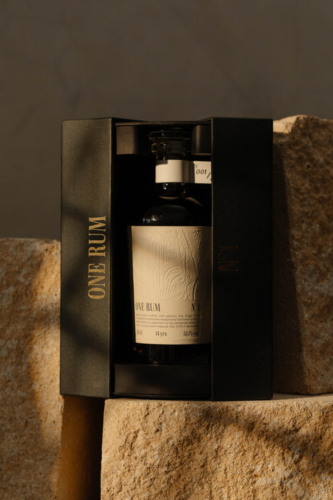ONE RUM No. 1 in einer schwarzen Geschenkbox, elegant auf Stein platziert. Die limitierte Abfüllung mit tropischem Prägungsmuster repräsentiert 14 Jahre gereiften, exklusiven Single Cask Rum.
