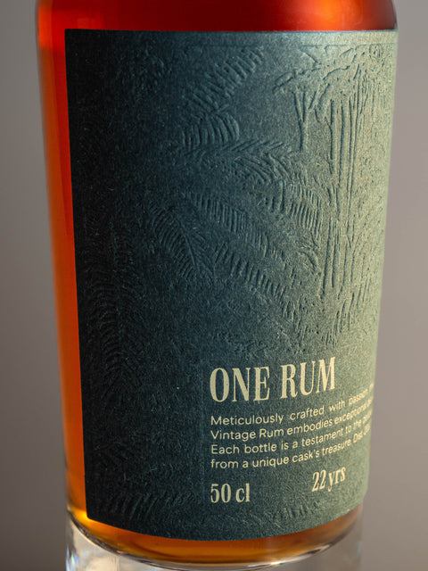 Detailansicht des Etiketts der ONE RUM No. 3 Flasche mit feinem tropischen Prägungsmuster auf grünem Hintergrund. Diese limitierte Abfüllung ist 22 Jahre gereift und repräsentiert die Exklusivität des Single Cask Rums.