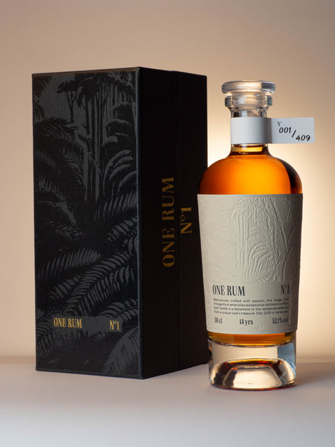 ONE RUM No. 1 Flasche und schwarze Geschenkbox mit tropischem Design, elegant arrangiert. Die Flasche trägt die Nummer 001/409 und enthält einen 14 Jahre gereiften, limitierten Single Cask Rum mit 52,1% vol., destilliert in Venezuela.