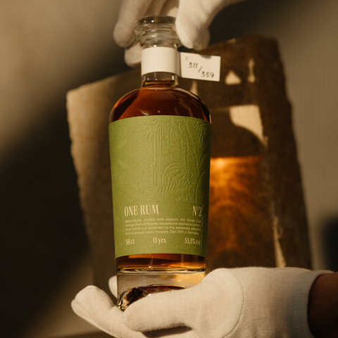 Eine Flasche ONE RUM No. 2, 13 Jahre gereift, wird von einer Hand mit weißen Handschuhen gehalten. Der grüne Etikettentext und die Seriennummer 311/359 heben die Exklusivität dieses limitierten Single Cask Rums hervor.