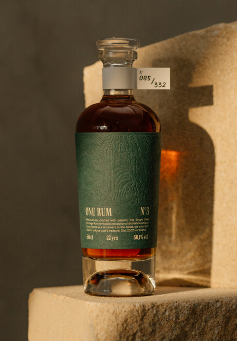 ONE RUM No. 3 Flasche, 22 Jahre gereift, mit tiefgrünem Etikett und Nummerierung 085/332, arrangiert auf einem Stein. Der hochwertige Single Cask Rum aus Panama hat einen Alkoholgehalt von 60,1% vol. und zeigt die Eleganz der Marke.